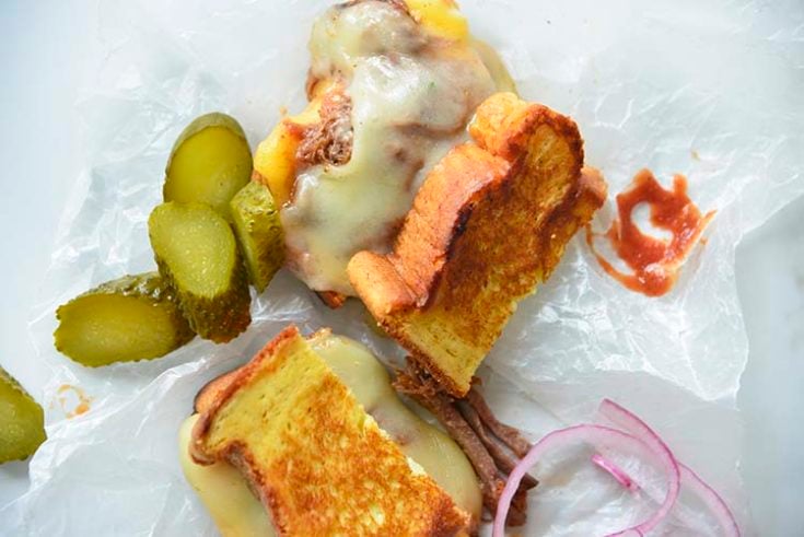 3 cheese keto grilled cheese sandwich on parchment paper with pickles and red onions