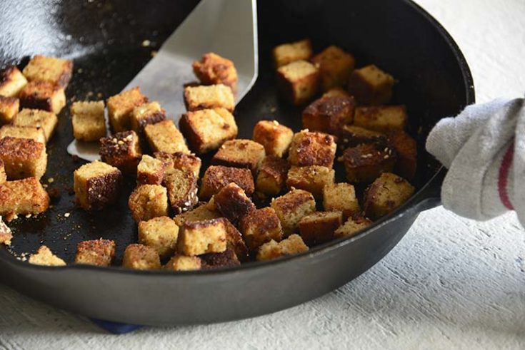 bacon croutons in a cast iron skillet with a wood handled spatula