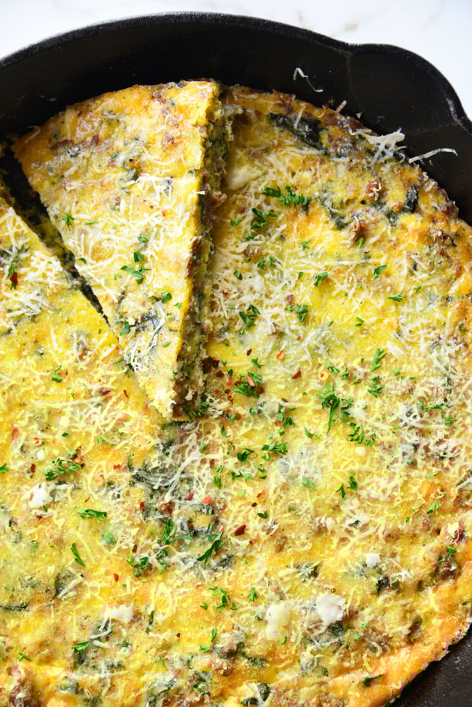 vertical image of a baked frittata in a cast iron skillet close up