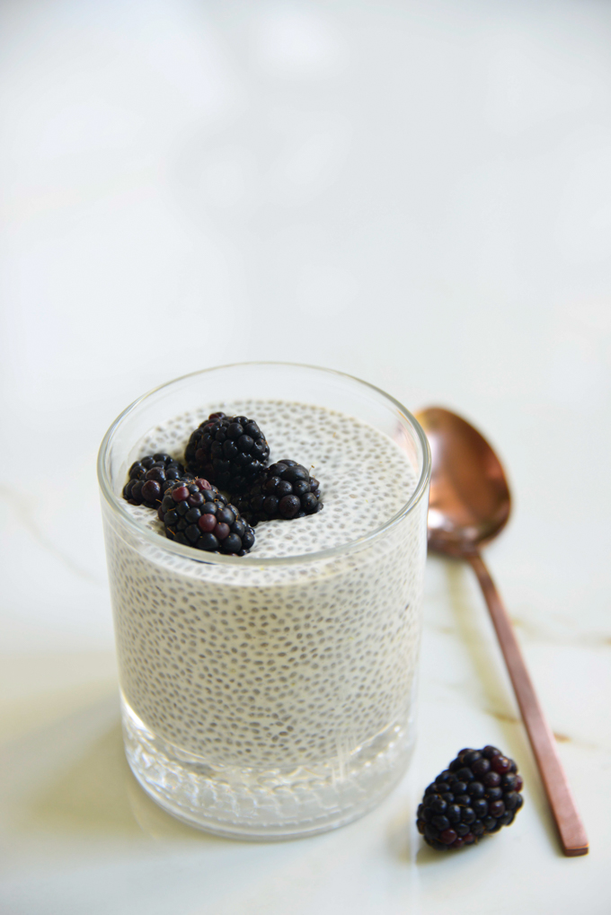 blackberry lemon chia pudding in a glass with a spoon and blackberries on top