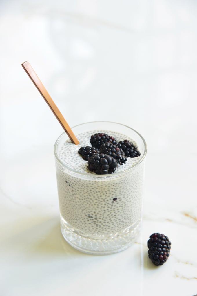 blackberry lemon chia pudding in a glass with a spoon and blackberries on top