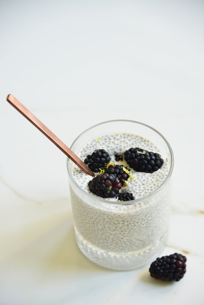 blackberry lemon chia pudding in a glass with a spoon and blackberries on top