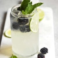 Blackberry Mojito Mocktail recipe in a clear glass garnished with mint, lime and blackberries