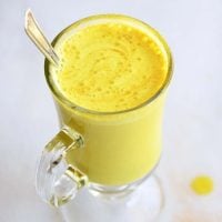 image of golden milk latte in a clear glass on a white background