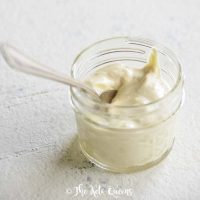 featured image of creamy caesar salad dressing in a glass mason jar with a spoon on a white surface