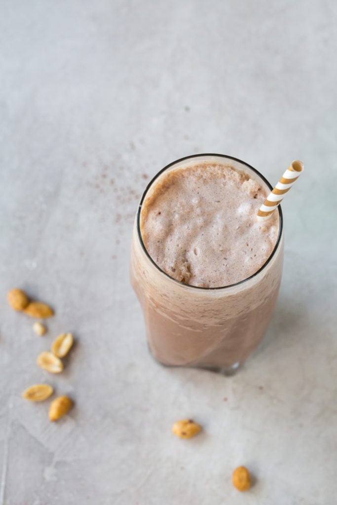 low carb chocolate peanut butter milkshake in a tall glass with a straw on a grey background