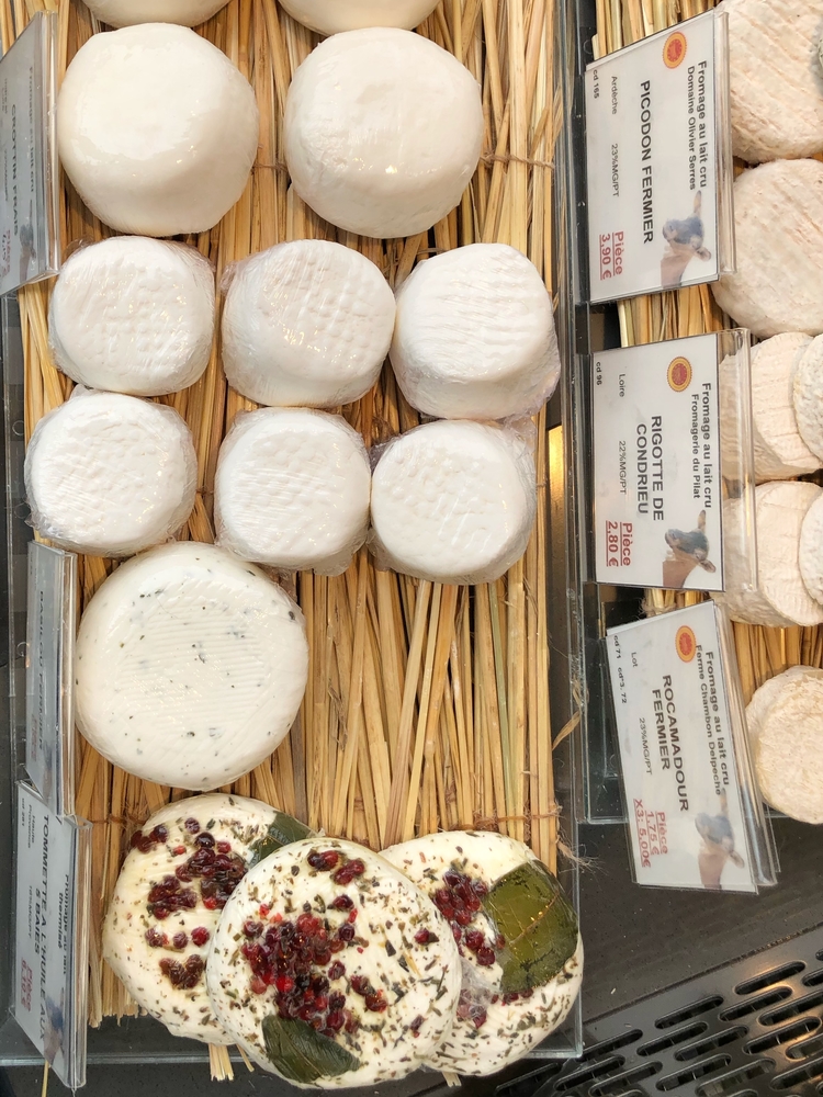 Top View of Different Types of Fromage au Lait Cru on Top of Straw in French Cheese Shop