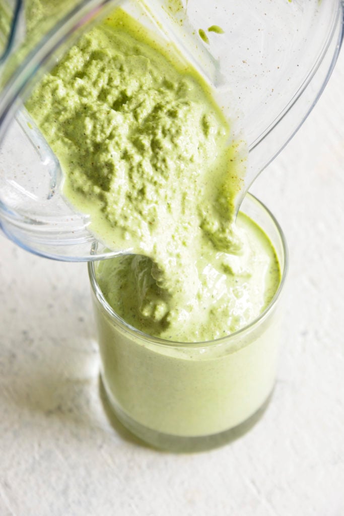 pouring a Keto Protein Green Smoothie into a clear glass