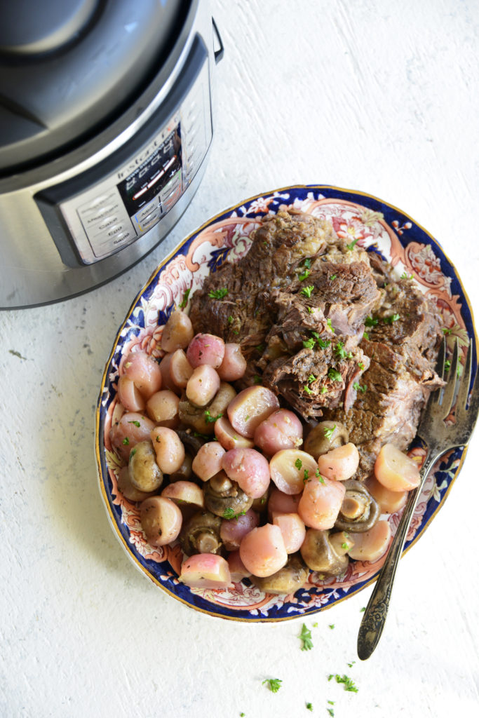 instant pot pot roast with radishes on a white background