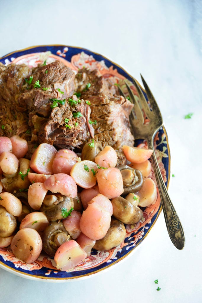 instant pot pot roast with radishes on a white background