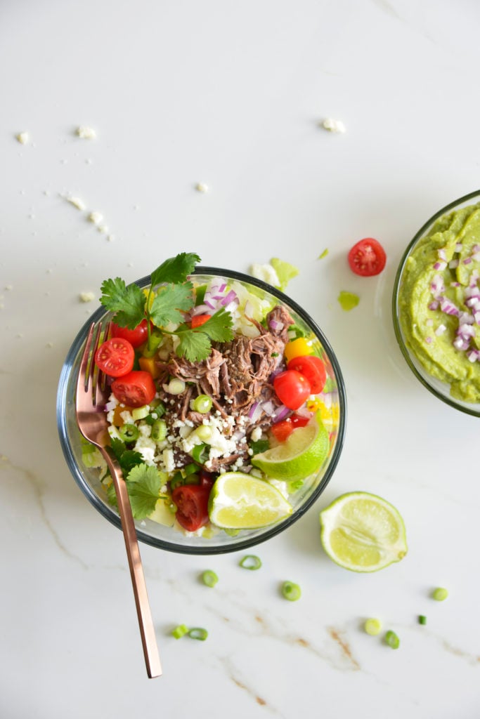 Shredded Beef Keto Taco Salad Recipe in a glass bowl with a fork on a white background with lime