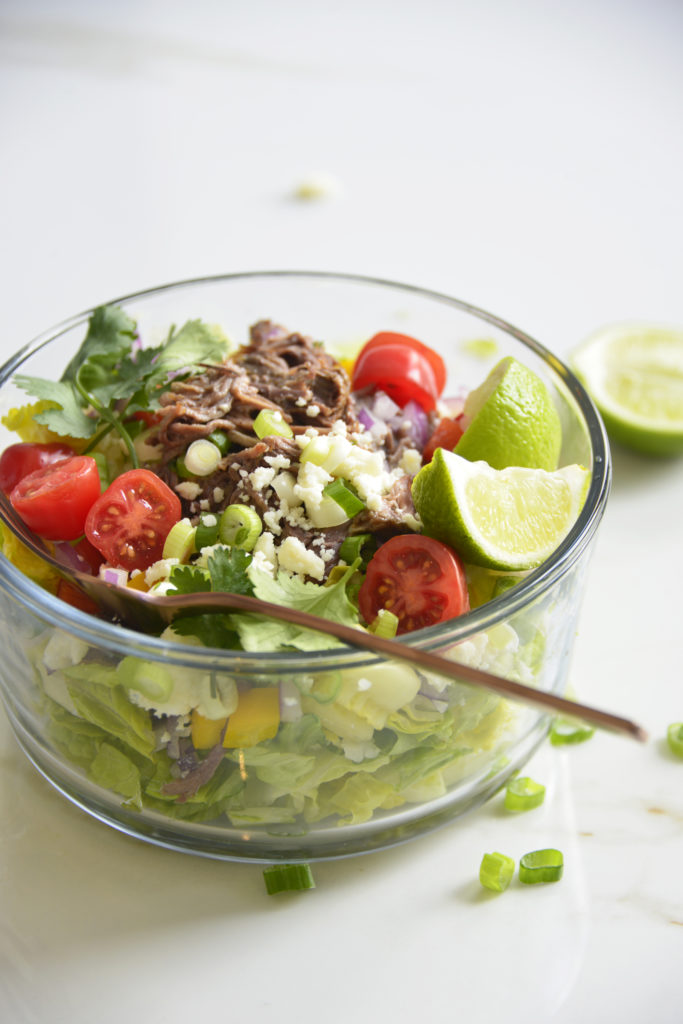 Shredded Beef Keto Taco Salad Recipe in a glass bowl on a white background with lime