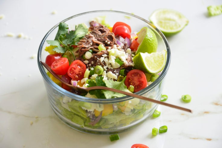 Shredded Beef Keto Taco Salad Recipe in a glass bowl on a white background with lime