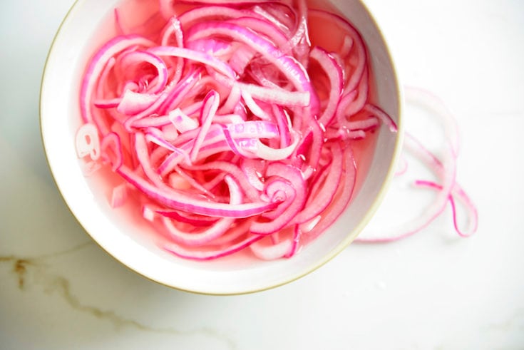 above shot of pickled red onions without sugar in a white bowl