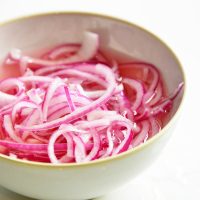 close up of pickled red onions in a white bowl