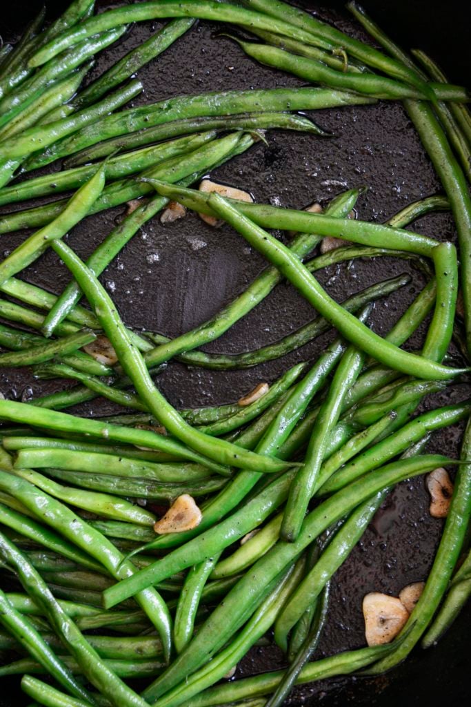 garlicky green beans cooked in a cast iron skillet
