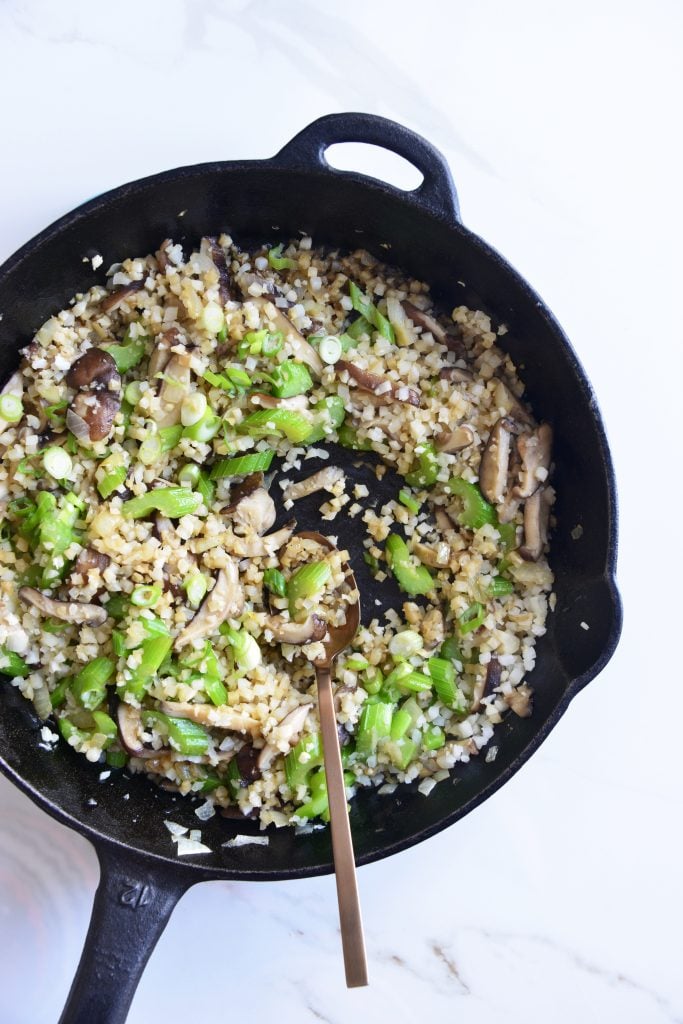 cauliflower fried rice in a cast iron skillet with a spoon