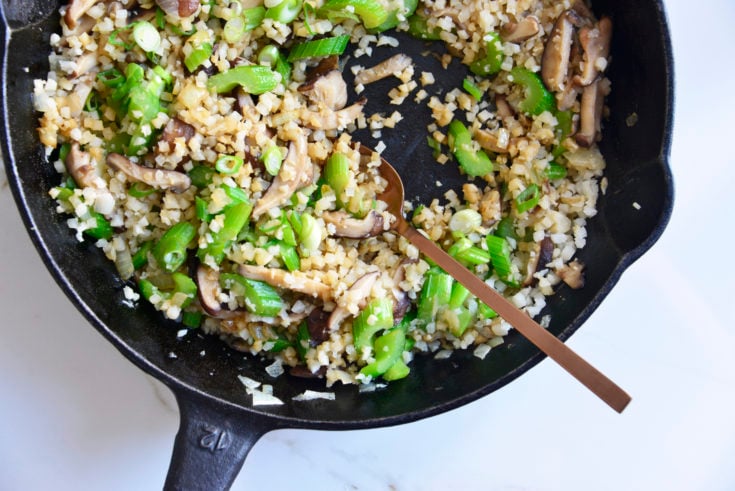 cauliflower fried rice in a cast iron skillet with a spoon