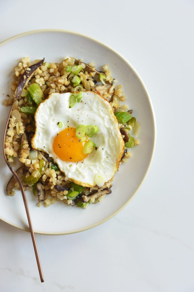 cauliflower fried rice on plate topped with an egg