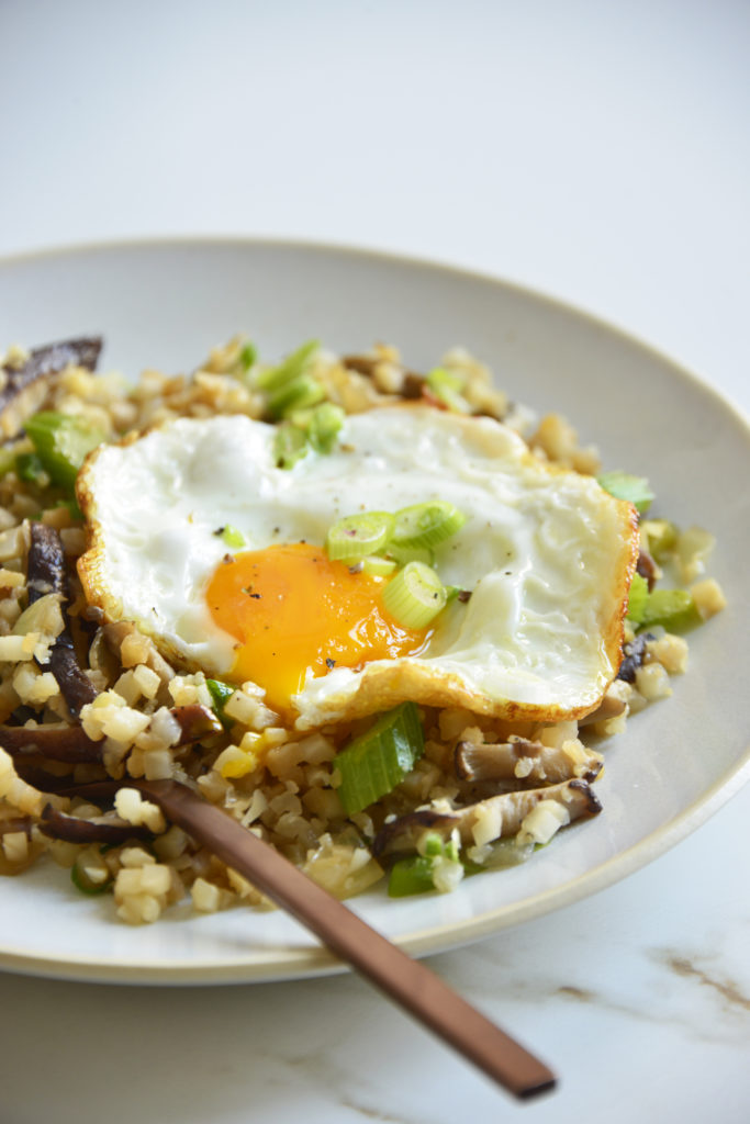 cauliflower fried rice on plate topped with an egg