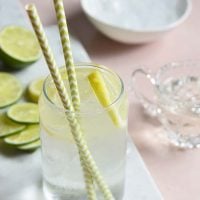 keto lemonade in a clear glass on a white slate with slices of lemon