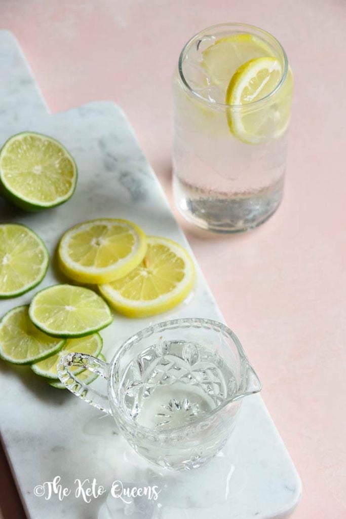 keto lemonade in a clear glass on a white slate with slices of lemon