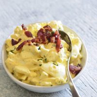 image of keto egg salad with bacon and a spoon on top