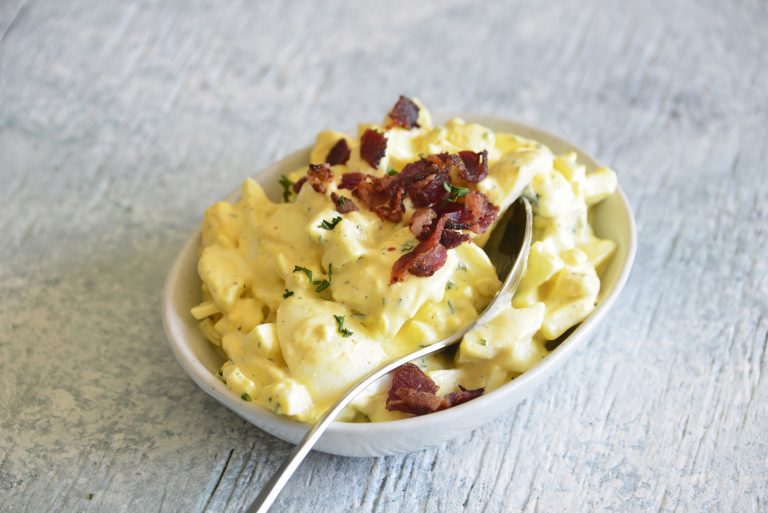 image of keto egg salad with bacon and a spoon on top