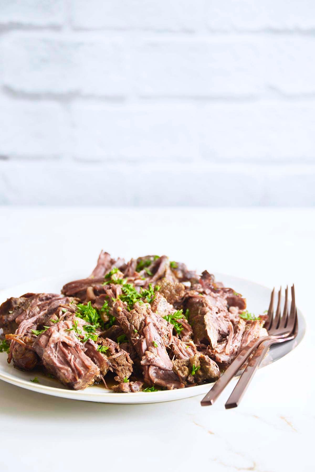 front view of plate of tender beef made in instant pot shredded with two forks