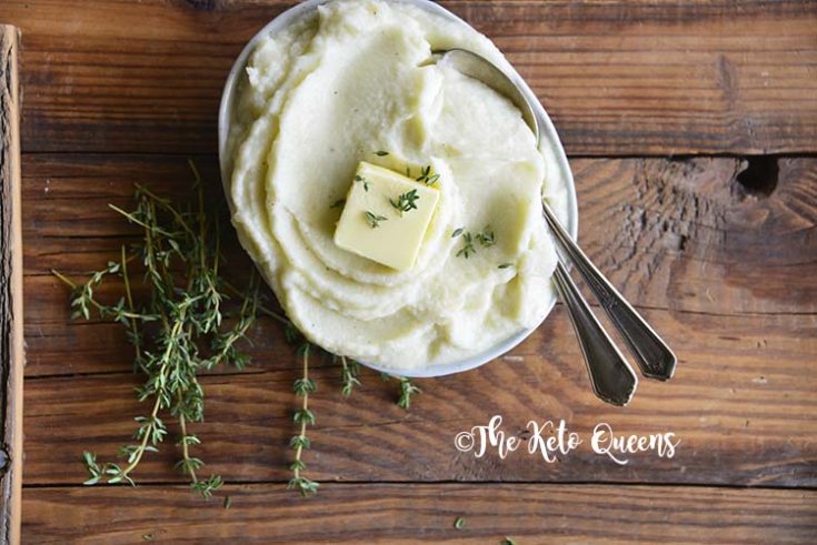 Pinterst image for low carb butter garlic mashed cauliflower Horizontal image of mashed cauliflower in a bowl with butter, thyme and 2 spoons