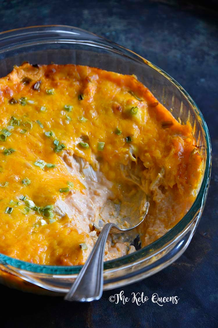 close up image of buffalo chicken dip in a glass bowl with a spoon