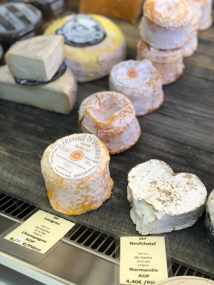 Langres and Neufchatel Cheeses on Wooden Shelf in Cheese Shop