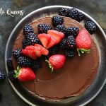 flourless chocolate cake with berries on top on a black background