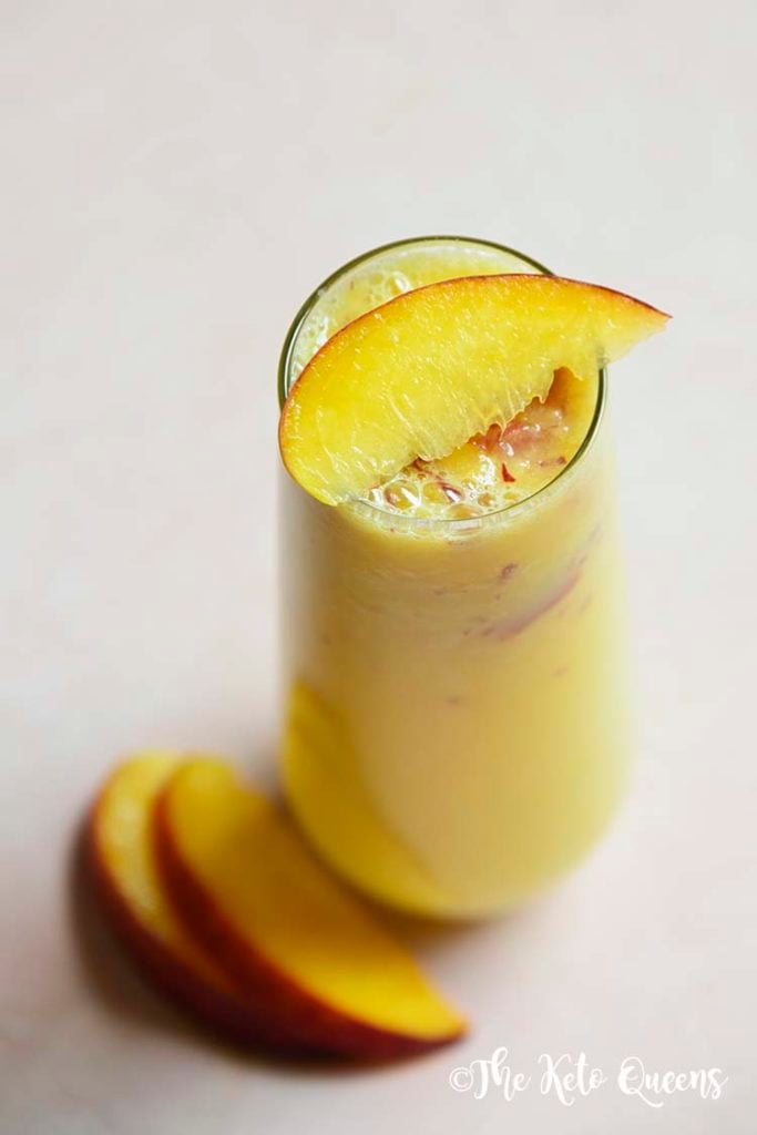 low carb peach bellini mocktail in a seamless glass with peaches on top