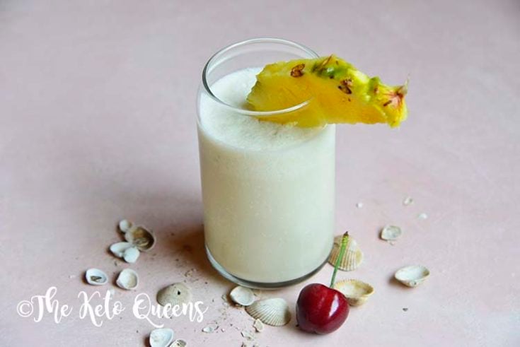 keto pina colada in a glass cup with pineapple and cherry