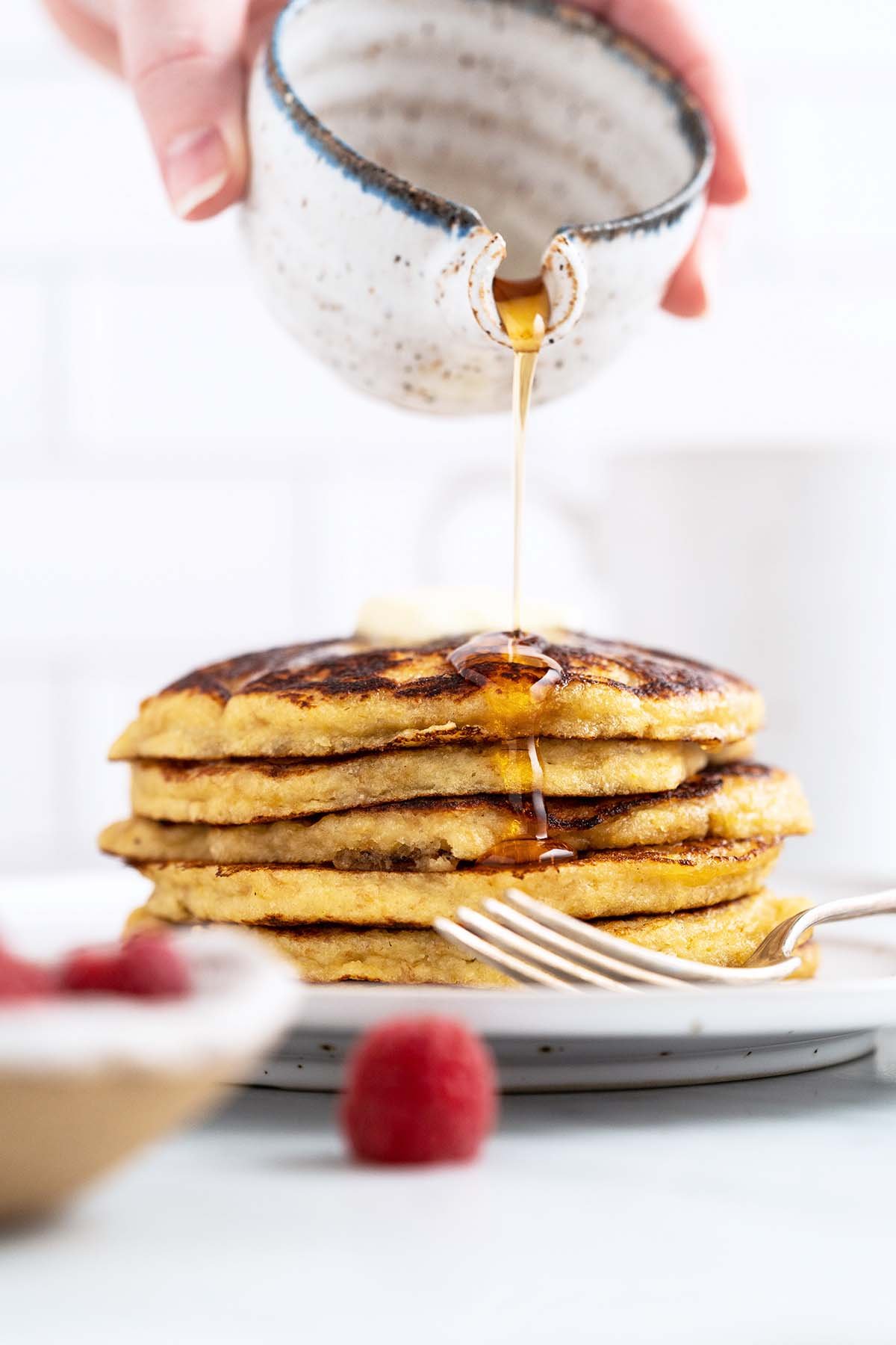 pouring syrup on stack of keto pancakes