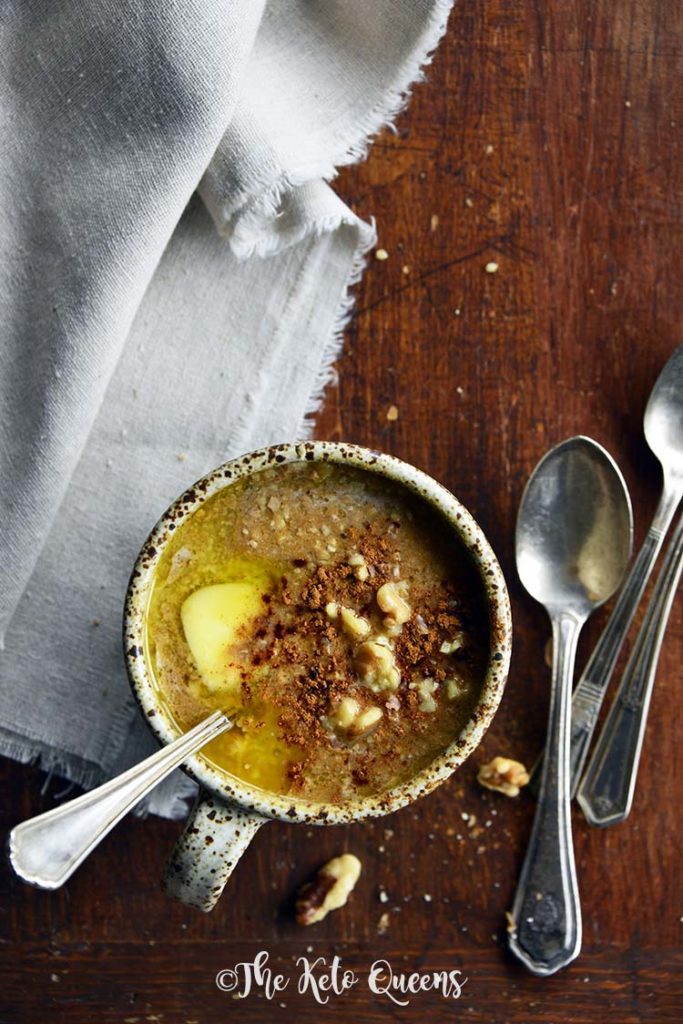 pumpkin spice keto oatmeal in a mug with spoons and linen on a wood surface