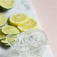 keto simple syrup in a glass with lemons and limes on a marble slate