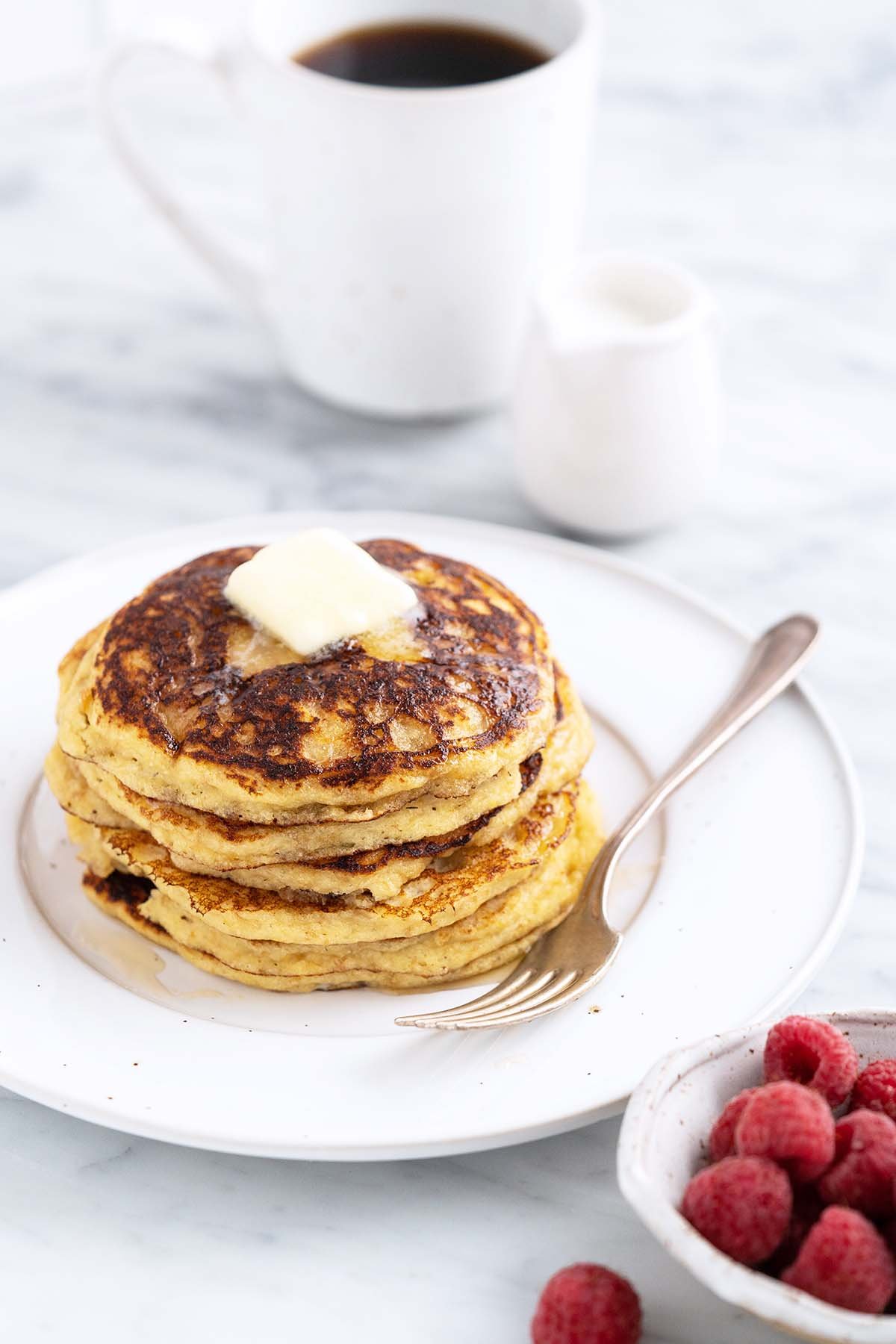 stack of keto pancakes on white plate with coffee and cream in background