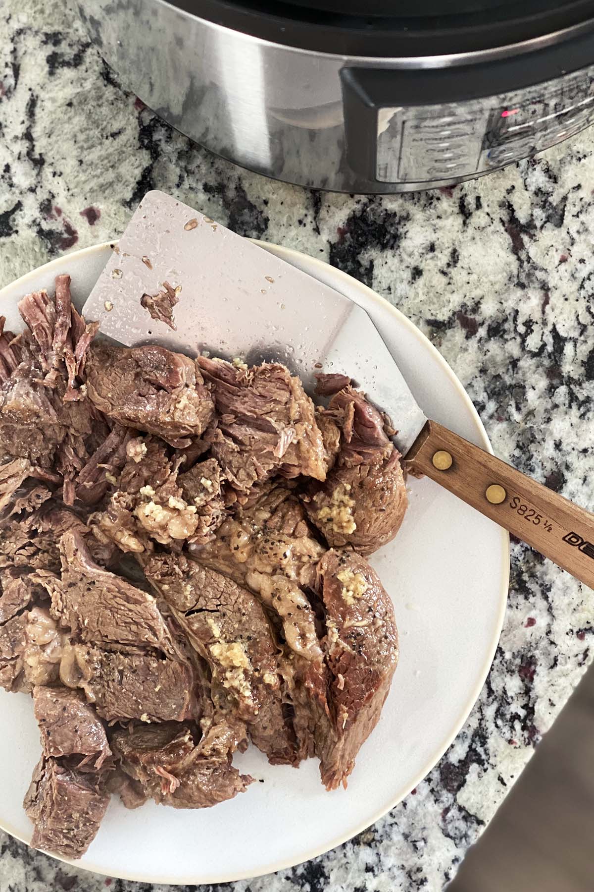 tender cooked chuck roast on plate next to instant pot