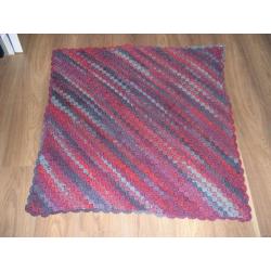 An unused hand crocheted chunky snuggle rug/throw in a mix of deep pinks/blues/ purples.